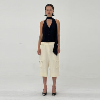 Woman wearing a navy sleeveless top and beige cargo pants on a white background