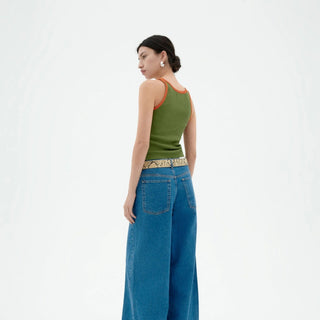 Woman wearing a green tank top and blue jeans on a white background